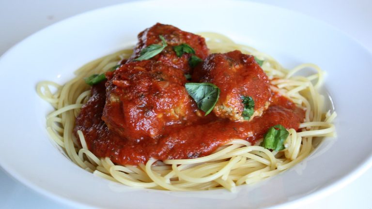 Kødboller i tomatsovs serveret på spaghetti med frisk basilikum