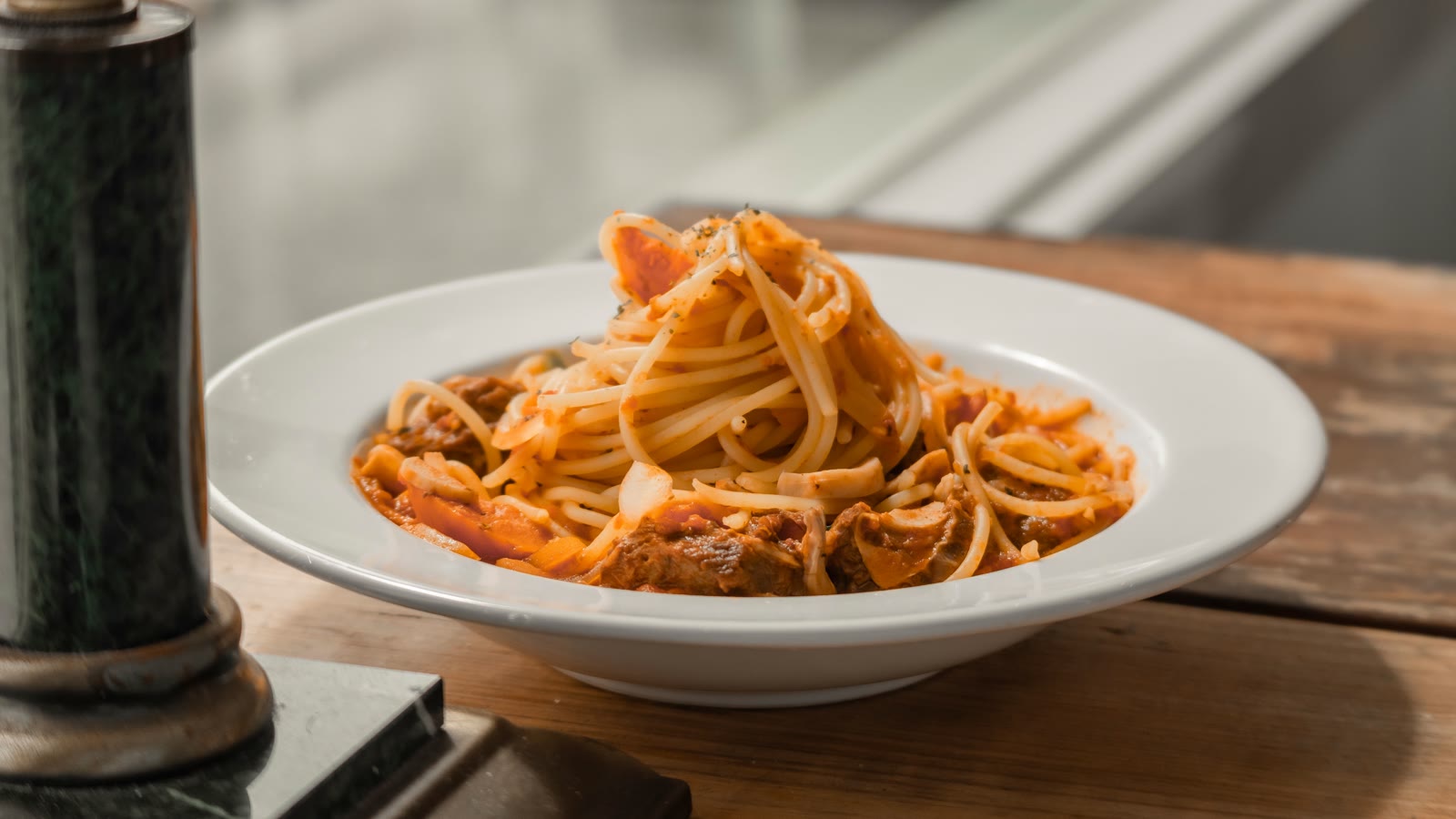 Spaghetti med kødsovs i en dyb tallerken på et træbord