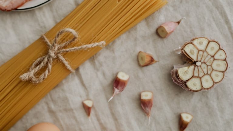 Bundt tørret spaghetti bundet med snor, hvidløg og æg på et lærredsklæde