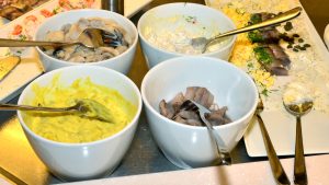 Skåle med karrysild, marinerede sild og sildesalat på et julefrokostbord med æg, dild og kapers